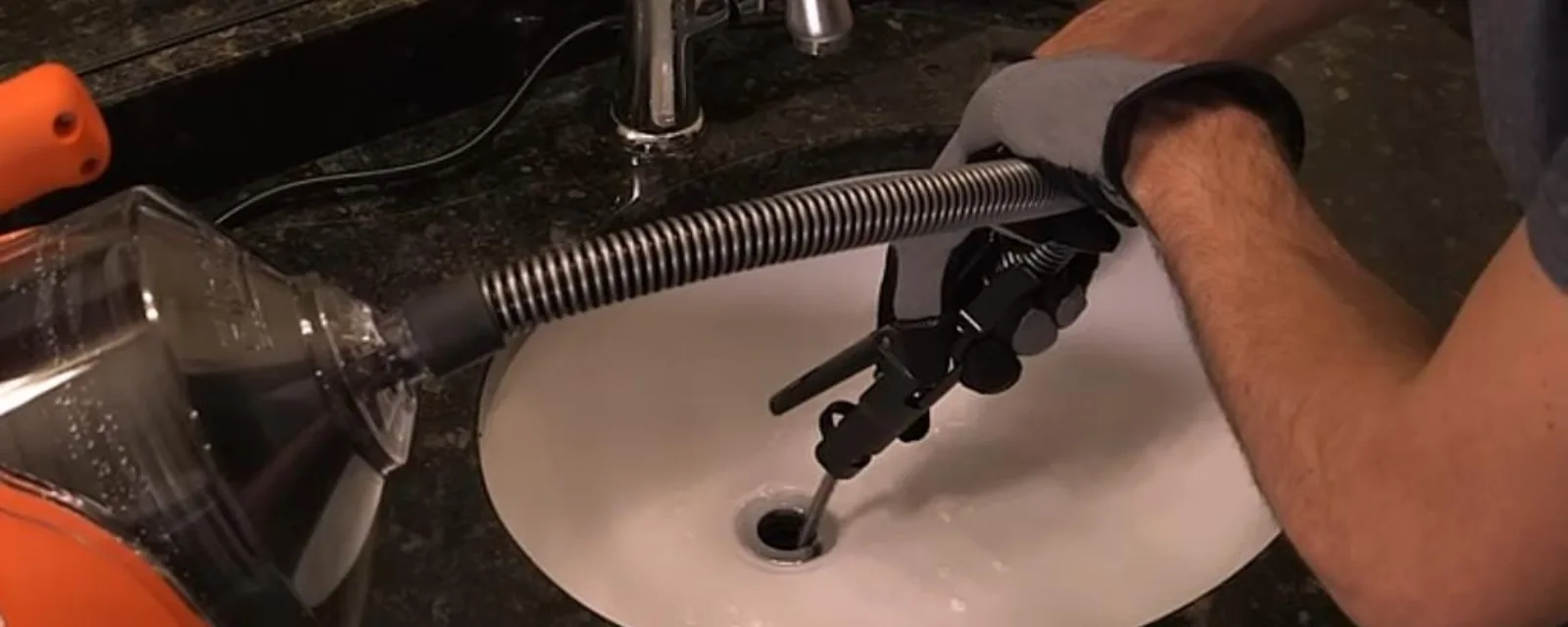 Plumber feeding a drain cable into a bathroom sink drain